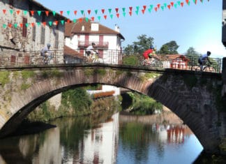 Guía del País Vasco para ciclistas británicos Cyclists crossing the picturesque bridge in the rural town of Saint Pied de Port in the Pyrenean foothills. Tourisme Béarn Pays Basque