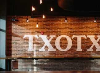 Importing the Txotx rite into North Carolina Una pared de la sidrería de Carolina del Norte, Black Twig Cider House, con la palabra "txotx "